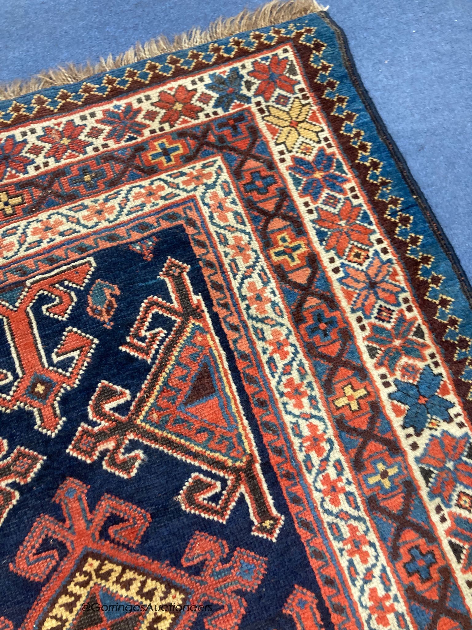 A Caucasian blue ground rug, woven with hooked lozenges, 288 x 152cm